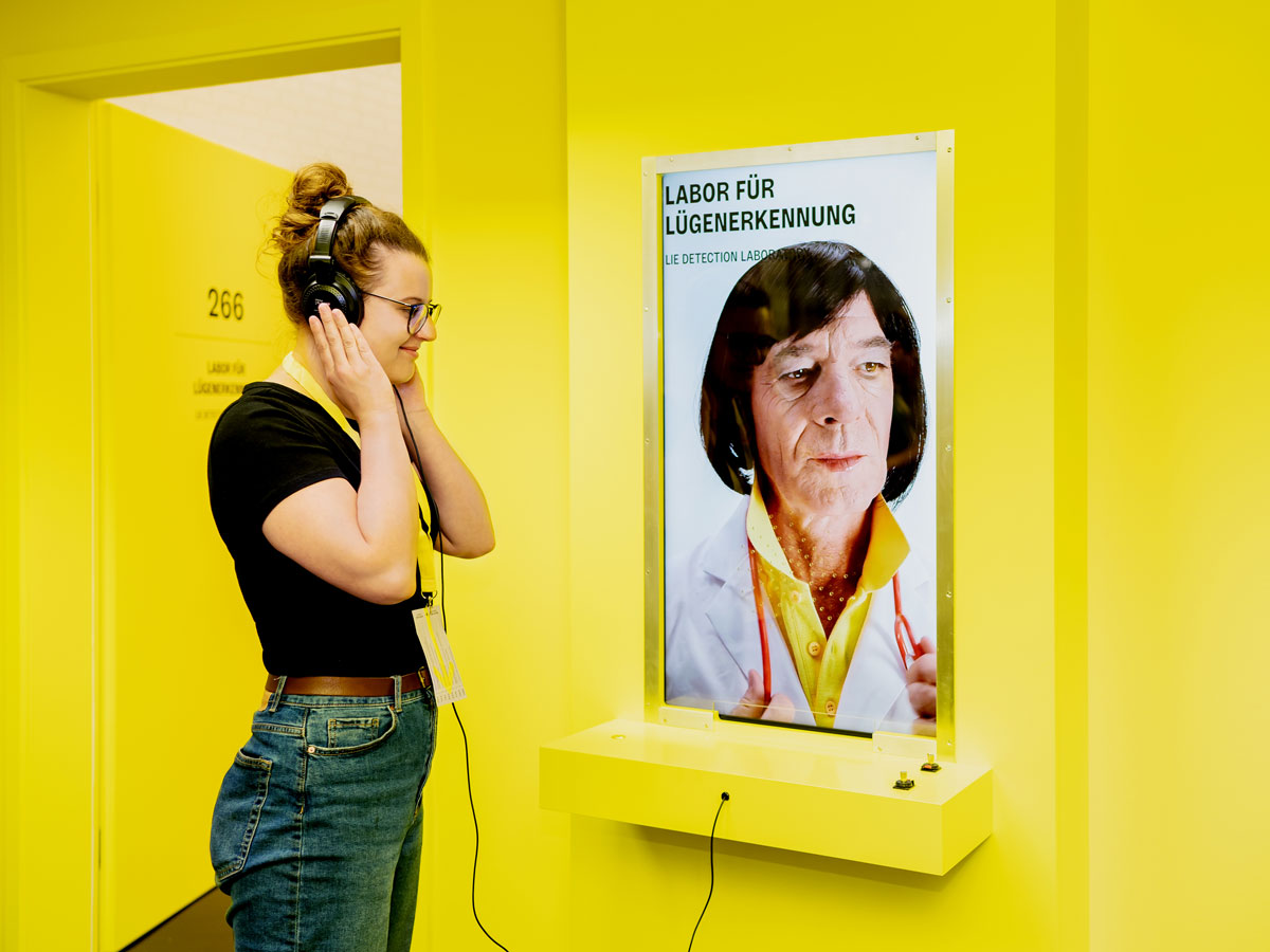 Frau an Hörstation in Ausstellung "Fake"