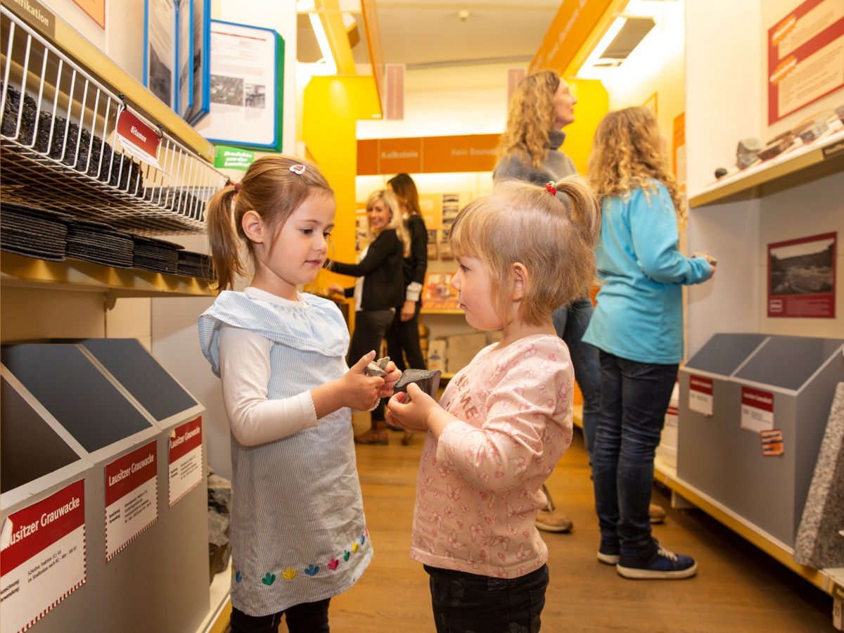 Zwei kleine Mädchen stehen in einem Museum und betrachten alte Steine.