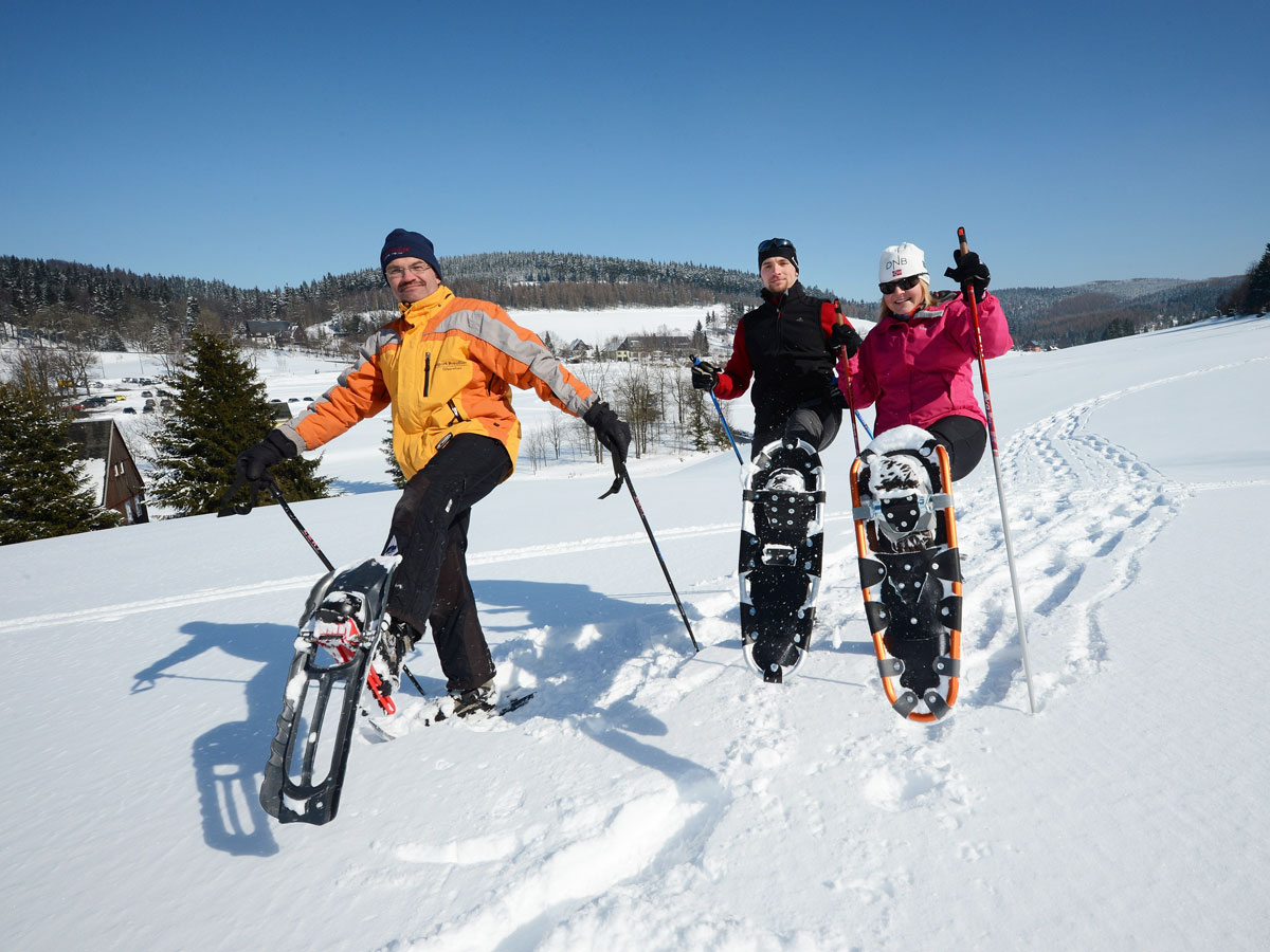 Guide und zwei Teilnehmer bei einer geführten Schneeschuhwanderung